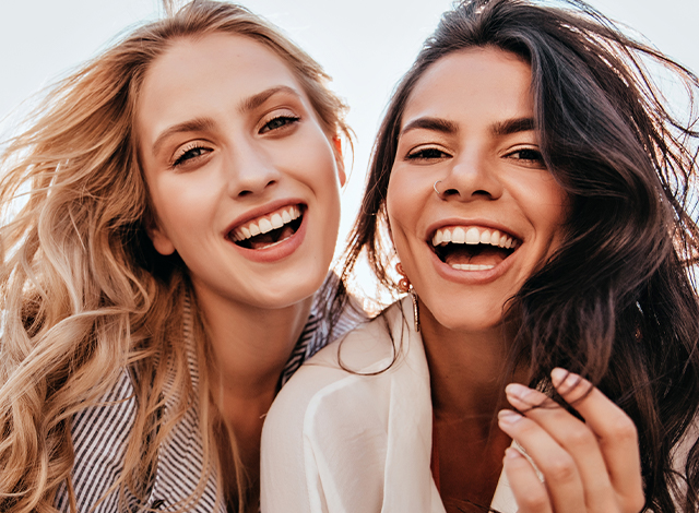 Two women with big smiles close together. benefits of a med spa